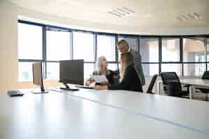 Free photo managers discussing reports with boss, sitting at meeting table with monitor and holding documents. business meeting or teamwork concept