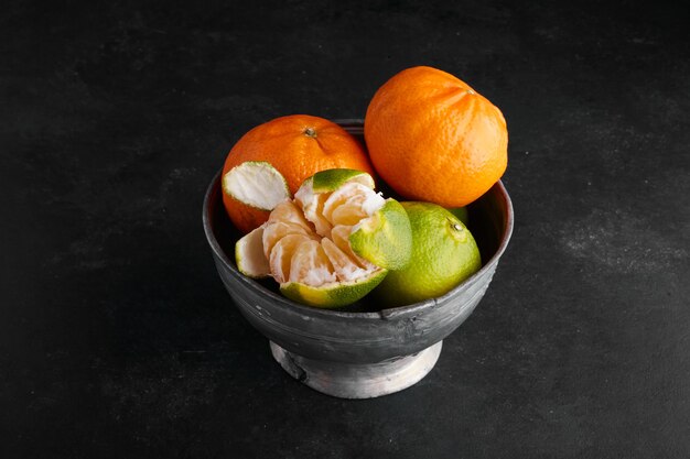 Mandarin oranges in a metallic cup on the table. 