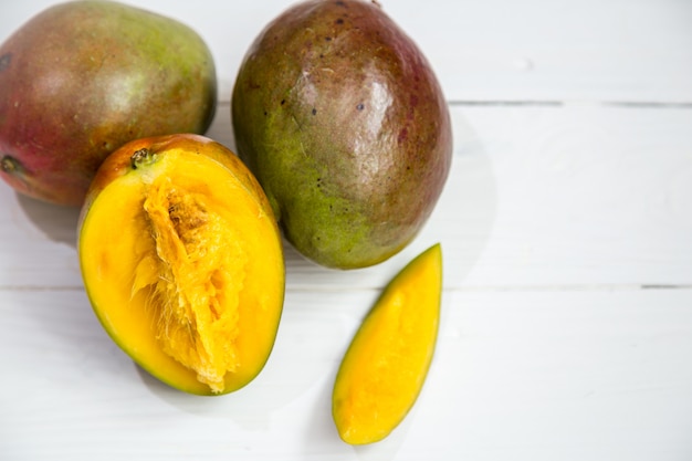 Free photo mango fruits closeup on white wooden background,