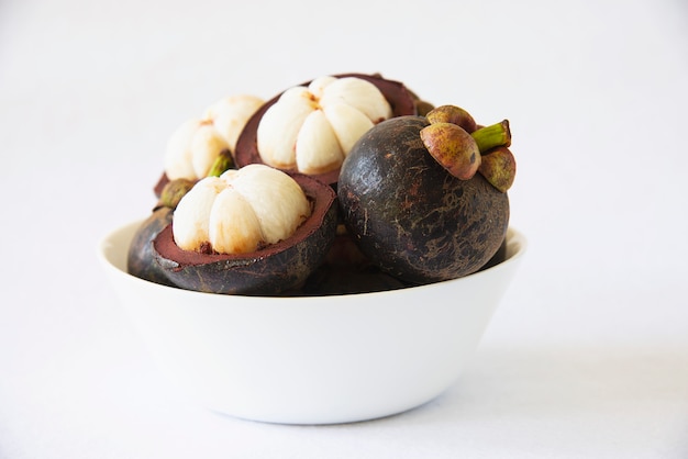 Free photo mangosteen thai popular fruits - a tropical fruit with sweet juicy white segments of flesh inside a thick reddish-brown rind.