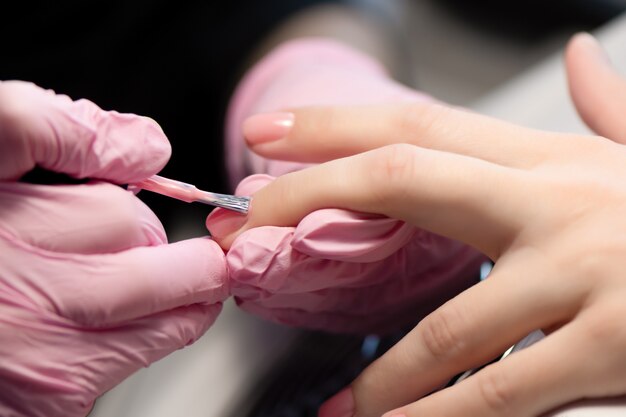 Manicurist doing gel nail design for client, close up.