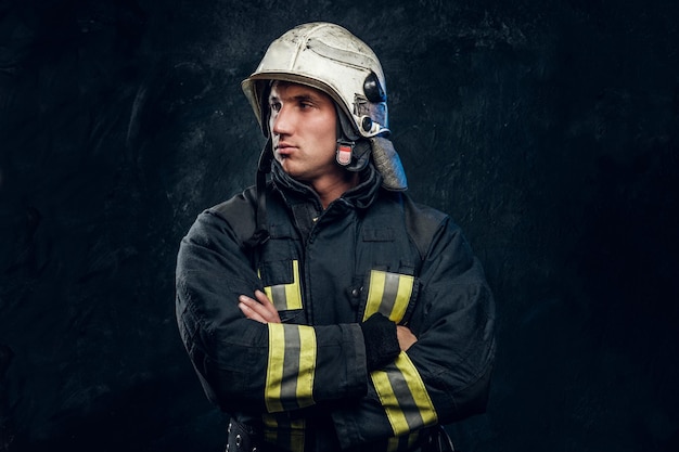 Free photo manly firefighter in helmet looks sideways in studio on black background