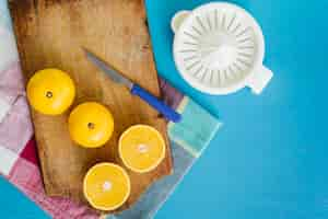 Free photo manual juicer near sweet limes on cutting board over blue background