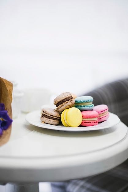 Free photo many colorful macaroons on white ceramics plate over the table