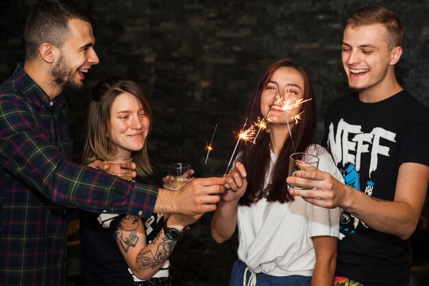 Many happy friends holding drinks lighting sparkle