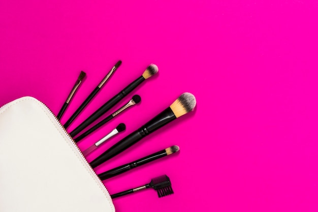 Free Photo many makeup brushes out of white bag over the pink backdrop