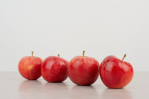 Many of red apples on white table.