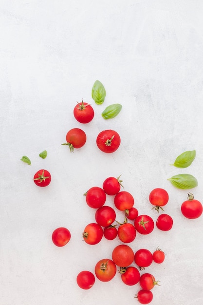 Free photo many red tomatoes with basil leaves on textured background