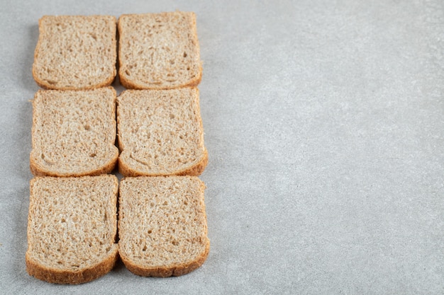 Free photo many of slices of brown bread on a gray background.