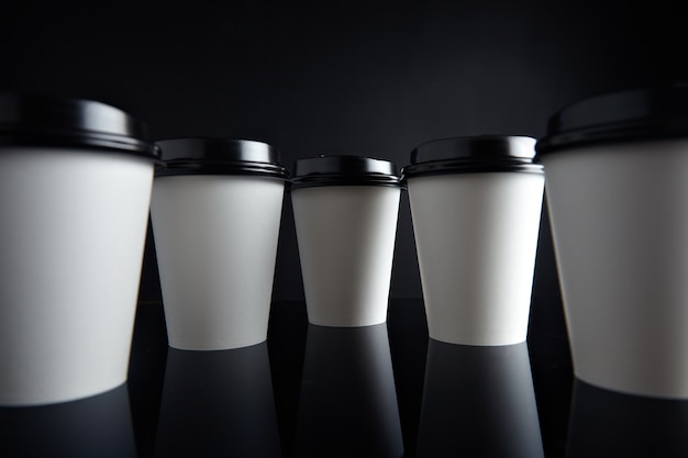 Many white take away paper cups for hot beverages closed with caps presented in parallax perspective