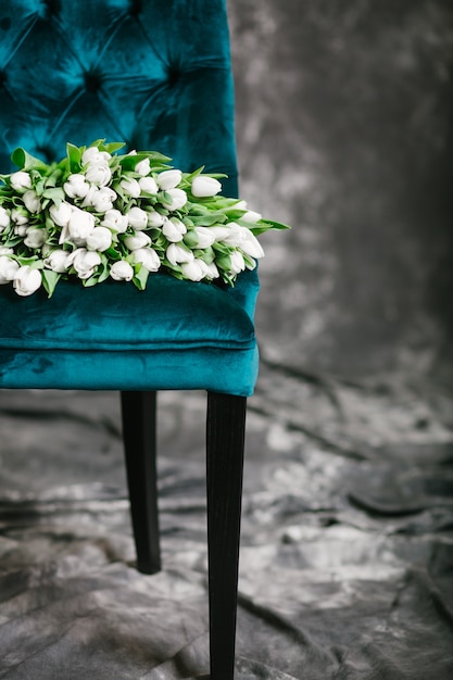 Free photo many white tulips on a green chair on a gray background