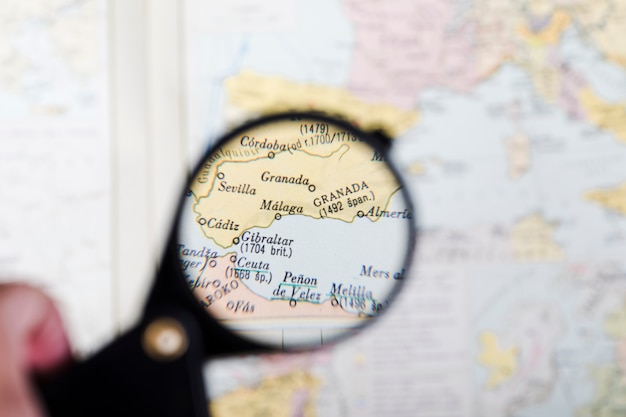 Map of Spanish cities seen through magnifying glass hold by person