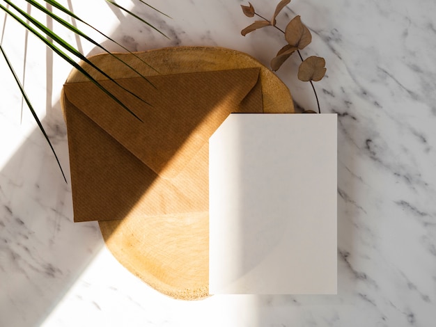 Marble background with a wooden plate with a brown envelope and a white blank