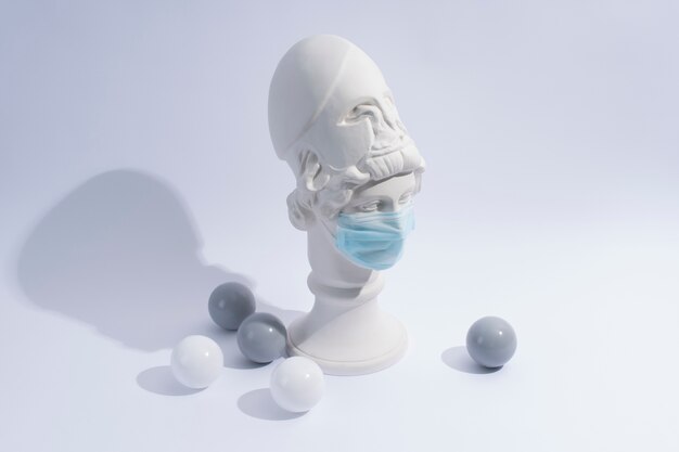 Marble sculpture of historical figure with medical mask and balls