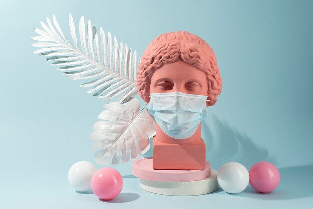 Marble sculpture of historical figure with medical mask and feathers