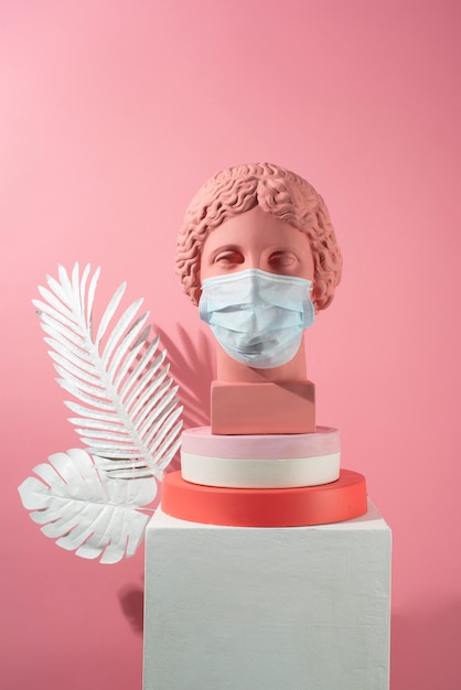 Marble sculpture of historical figure with medical mask and feathers