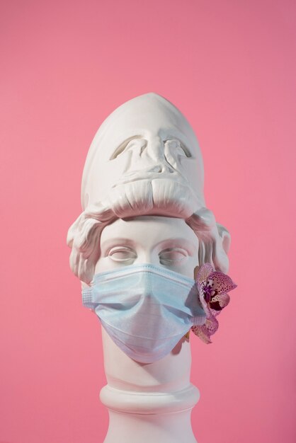 Marble sculpture of historical figure with medical mask and orchid