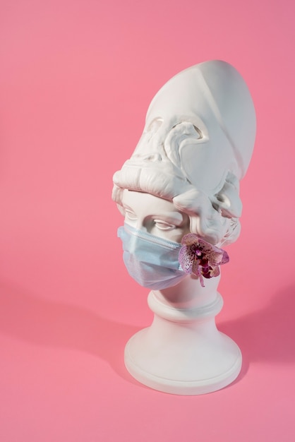 Free Photo marble sculpture of historical figure with medical mask and orchid