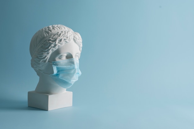 Marble sculpture of historical figure with medical mask