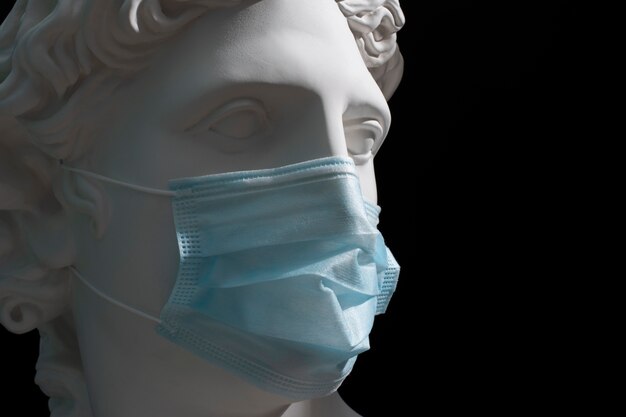 Marble sculpture of historical figure with medical mask