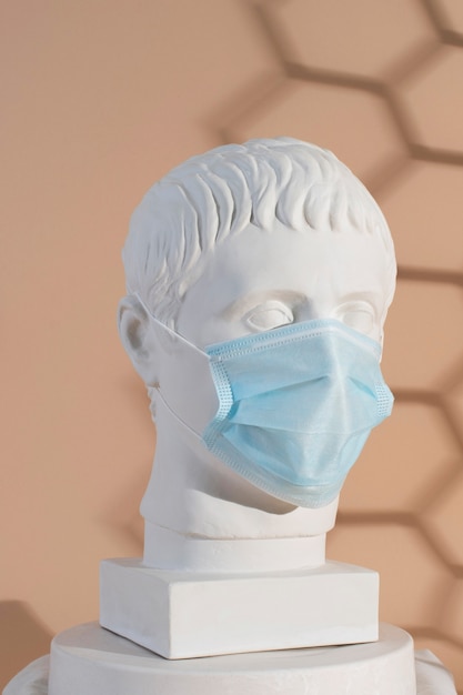 Marble sculpture of historical figure with medical mask