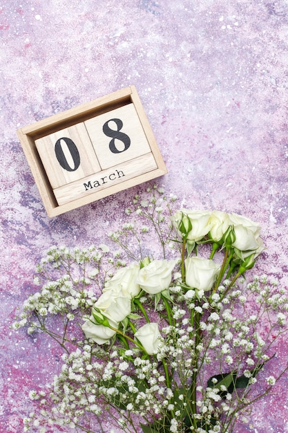 Free photo march 8 women's day card with white flowers,sweets and a cup of tea .