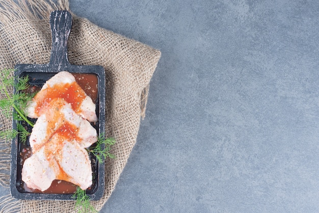 Free Photo marinated chicken wings with sauce on black board.