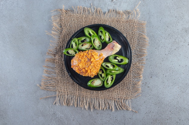 Free Photo marinated drumstick and sliced pepper on a plate on the burlap napkin , on the marble surface.