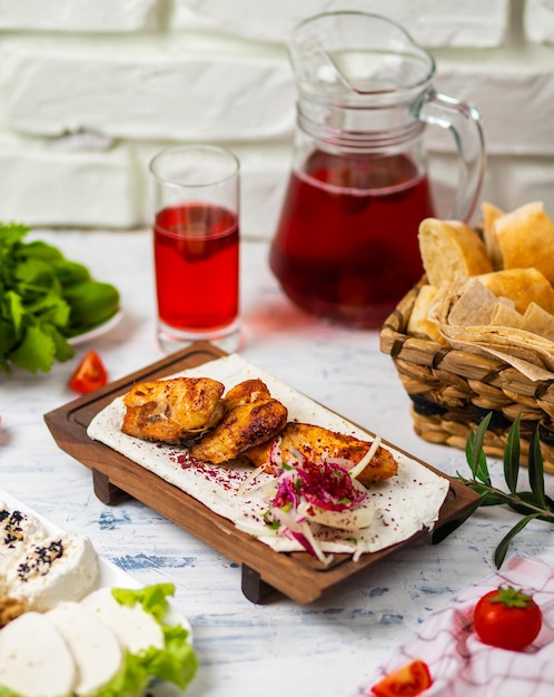 Marinated grilled healthy chicken breasts cooked on a summer BBQ and served in lavash with fresh herbs, wine, bread on a wooden board, close up view