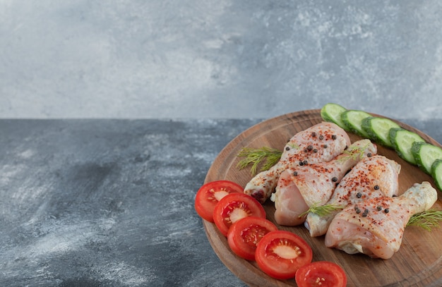 Free photo marinated raw chicken drumstick on wooden board.