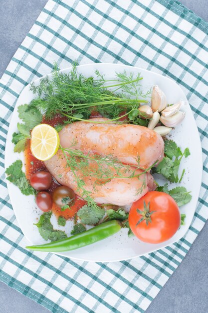 Marinated whole chicken on plate with vegetables.