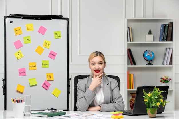 Free photo marketing pretty young blonde girl in grey suit in the office smiling