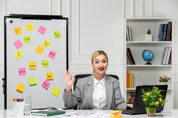 Marketing pretty young blonde girl in grey suit in the office very friendly saying hi