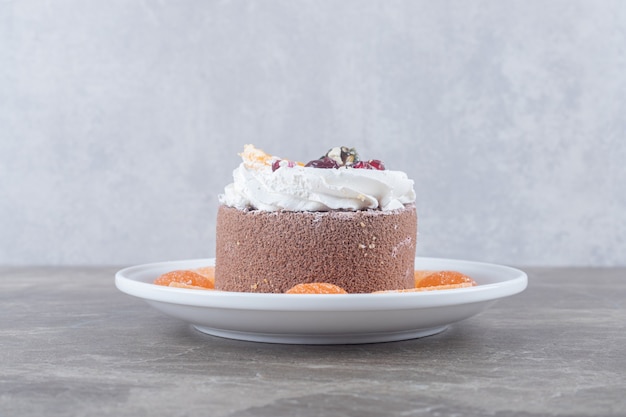 Marmelades around a small cake on a platter on marble surface