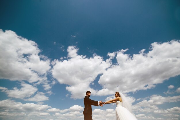 Married couple holding hands with clouds in the sky