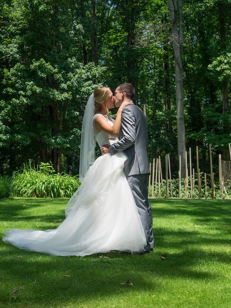 Married couple kissing in a garden surrounded by greenery under sunlight