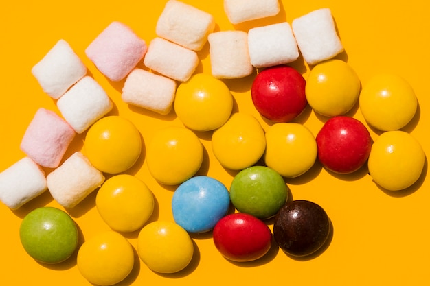 Free photo marshmallow and colorful candies on yellow background