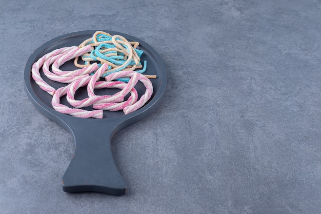 Free photo marshmallow colorful twisted rainbow ropes in a pan on marble table.