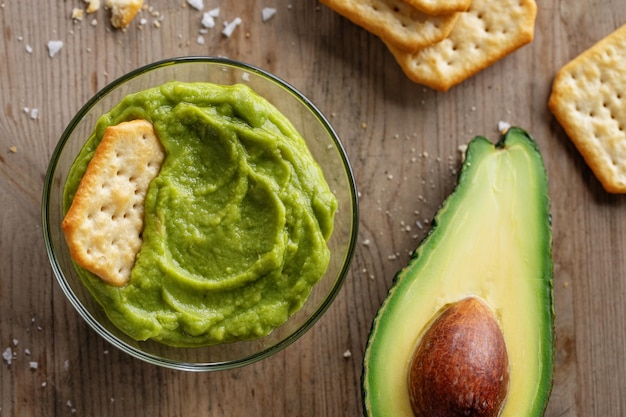 Free photo mashed avocado guacamole sauce in bowl with crackers.