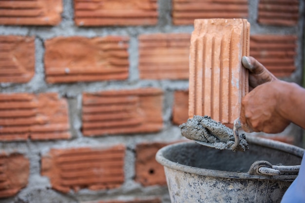 Masonry worker on the outside wall with a trowel knife.