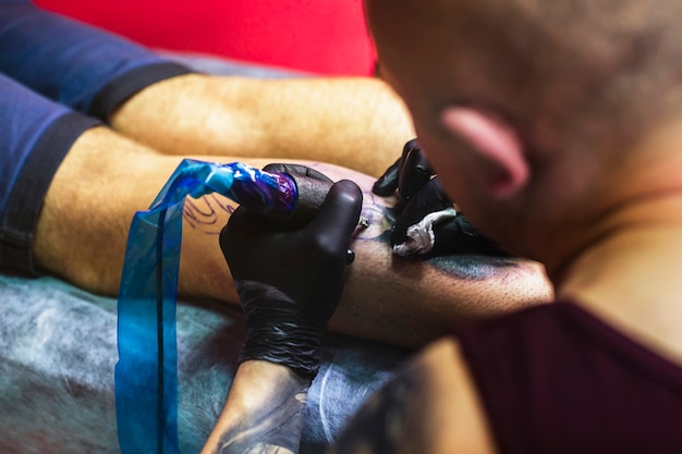 Master drawing tattoo on leg