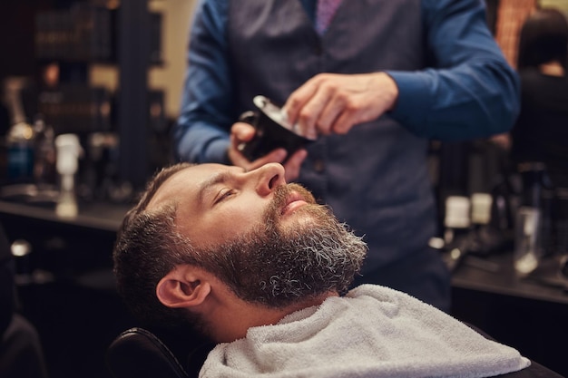 A master hairdresser prepares the face for shaving, deals foam.