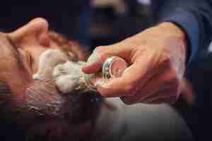 Free photo a master hairdresser prepares the face for shaving and smears the face with foam in a hairdressing salon.