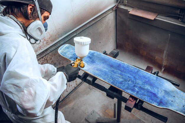 Master painter in a factory - industrial painting wood with spray gun.