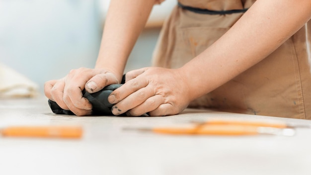 Free Photo the master of sculpting pottery working in a studio kneading a piece of clay with her hands tools