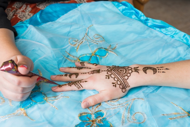 Master tattooing mehndi draws on lady hand