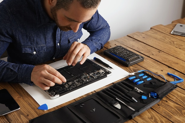 Free photo master uses angled esd tweezers to remove dust from electronic boards of broken slim computer laptop to fix it and make to work again