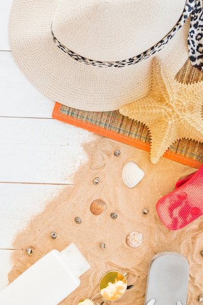 Free photo mat with hat and starfish near seashells and bottle on sand