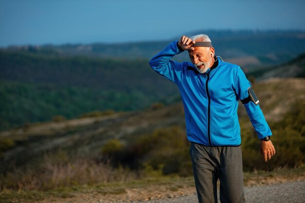 Mature athletic man feeling exhausted after jogging in the morning in nature Copy space