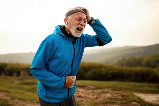 Mature athletic man suffering from headache while jogging in nature